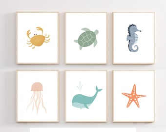 May include: Set of six printable wall art prints featuring illustrations of sea creatures. The prints include a crab, a turtle, a seahorse, a jellyfish, a whale, and a starfish. The prints are in a minimalist style with a white background and simple line drawings.