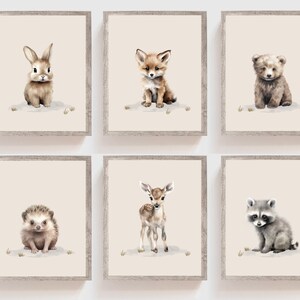 May include: Set of six framed prints featuring watercolor illustrations of baby animals, including a rabbit, fox, bear, hedgehog, deer, and raccoon. Each print has a light pink background and is framed in a light brown wood frame.