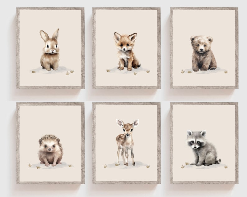 May include: Set of six framed prints featuring watercolor illustrations of baby animals, including a rabbit, fox, bear, hedgehog, deer, and raccoon. Each print has a light pink background and is framed in a light brown wood frame.