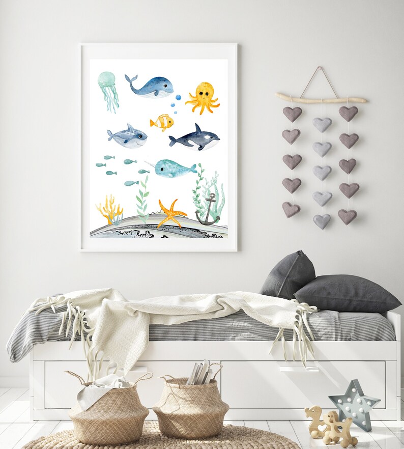 Peut inclure: Une impression aquarelle d'une vari&eacute;t&eacute; de cr&eacute;atures marines, dont une baleine, une narval, une m&eacute;duse, une pieuvre, une &eacute;toile de mer et une ancre. L'impression est sur fond blanc et encadr&eacute;e dans un cadre blanc.