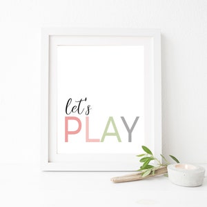 May include: White framed print with the text "let's PLAY" in pink, gray, and green lettering.