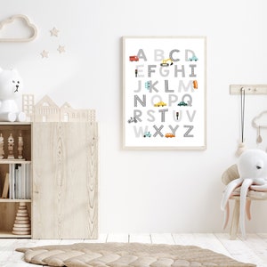 Puede incluir: Un p&oacute;ster del alfabeto enmarcado en blanco con ilustraciones coloridas de veh&iacute;culos para cada letra. El p&oacute;ster est&aacute; colgado en una pared blanca en una guarder&iacute;a.