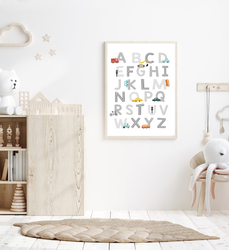 Puede incluir: Un p&oacute;ster del alfabeto enmarcado en blanco con ilustraciones coloridas de veh&iacute;culos para cada letra. El p&oacute;ster est&aacute; colgado en una pared blanca en una guarder&iacute;a.