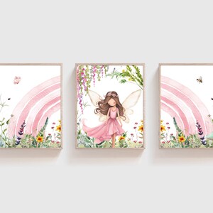 May include: Three watercolor paintings depicting a fairy with pink wings and a pink dress standing in a field of flowers with a pink rainbow in the background. The fairy is surrounded by green leaves and flowers. The paintings are framed in wood.