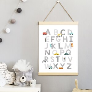 Puede incluir: Un p&oacute;ster blanco con un alfabeto gris impreso en &eacute;l. Cada letra est&aacute; rodeada de un camino gris con un peque&ntilde;o veh&iacute;culo o se&ntilde;al de tr&aacute;fico. El p&oacute;ster est&aacute; colgado en una pared gris con una cuerda.