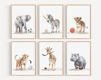 May include: Set of six watercolor animal prints featuring a zebra, lion, elephant, giraffe, cheetah, and hippopotamus, each playing a different sport. The prints are in a minimalist style with a white background and a wooden frame.