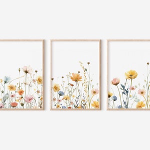 May include: Set of three framed watercolor prints featuring a floral design with yellow, orange, pink, and blue wildflowers on a white background.