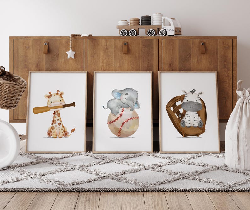 K&ouml;nnte beinhalten: Drei Aquarelldrucke mit einer Giraffe, die einen Baseballschl&auml;ger h&auml;lt, einem Elefanten, der auf einem Baseball sitzt, und einem Zebra, das in einem Baseballhandschuh sitzt. Die Drucke sind gerahmt und auf einem Holzregal ausgestellt.