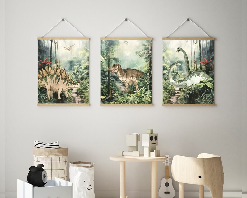 K&ouml;nnte beinhalten: Drei gerahmte Drucke von Dinosauriern in einer Dschungelkulisse. Die Drucke zeigen einen Stegosaurus, einen Tyrannosaurus Rex und einen Brachiosaurus. Die Drucke sind alle im Aquarellstil gehalten und haben ein gr&uuml;n-braunes Farbschema.