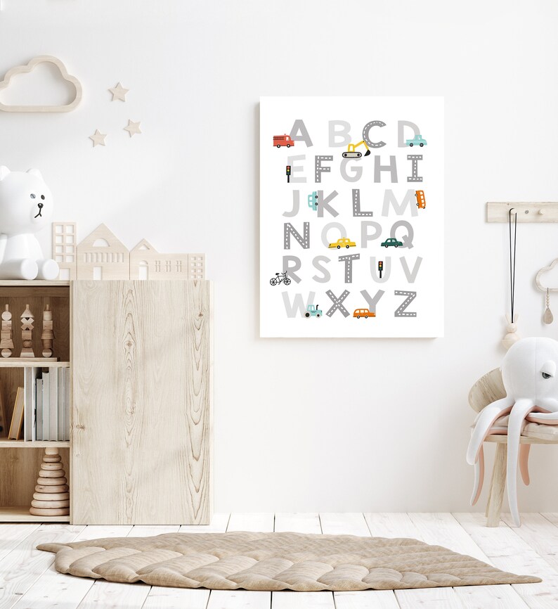 Puede incluir: Un p&oacute;ster de alfabeto blanco y gris con veh&iacute;culos coloridos y se&ntilde;ales de tr&aacute;fico. Las letras est&aacute;n en una fuente gris y los veh&iacute;culos son de varios colores, incluyendo rojo, azul, amarillo y verde. El p&oacute;ster est&aacute; colgado en una pared blanca en una guarder&iacute;a.