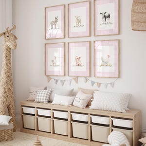 May include: A children's room featuring framed watercolor prints of farm animals, including a donkey, sheep, cow, goose, pig, and chicken. The prints have pink gingham borders. Below, a wooden storage unit with white bins and decorative pillows.