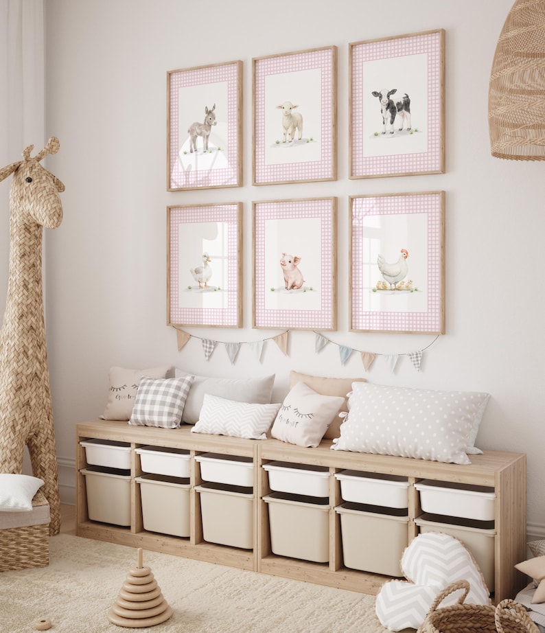 May include: A children's room featuring framed watercolor prints of farm animals, including a donkey, sheep, cow, goose, pig, and chicken. The prints have pink gingham borders. Below, a wooden storage unit with white bins and decorative pillows.