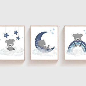 Op de afbeelding: Drie blauwe en grijze kinderkamerprints met een schattige grijze beer op een wolk, een halve maan en een regenboog. De prints zijn perfect voor een babykamer.