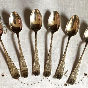 Peut inclure: Ensemble de six cuillères à café en argent avec des motifs ornés. Les cuillères ont un bol arrondi et un manche long et fin avec un motif décoratif.