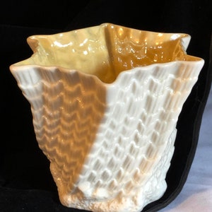 以下が含まれることがあります： 星型の開口部と幅広のベースを持つ、ユニークなテクスチャデザインの白と黄色のセラミック花瓶です。