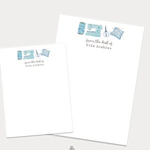 May include: Two blank stationery note cards featuring a blue watercolour illustration of a sewing machine, thread, scissors, and a pincushion. The text "from the desk of Erin Jenkins" is printed on both cards.