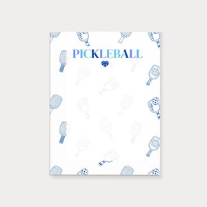 Könnte beinhalten: Ein weißer Hintergrund mit einem blauen und violetten Farbverlaufstext, der "PICKLEBALL" sagt, mit einem blauen Herzen unter dem Text. Der Hintergrund ist mit einem sich wiederholenden Muster aus blauen Schlägern und Bällen gefüllt.