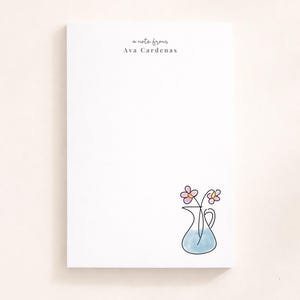 May include: A white notepad featuring the text "a note from Ava Cardenas". A blue vase with pink and yellow flowers is illustrated in the bottom right corner.