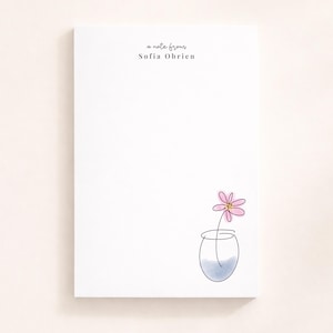 Puede incluir: Un bloc de notas blanco con el texto "a note from Sofia Obrien" en una escritura delicada. Un sencillo dibujo lineal de una flor rosa en un jarrón con agua azul se encuentra en la esquina inferior derecha.