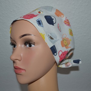 Peut inclure: Un bonnet de chirurgien blanc avec un motif coloré de tasses à thé et de théières. Le bonnet a une attache à l'arrière.