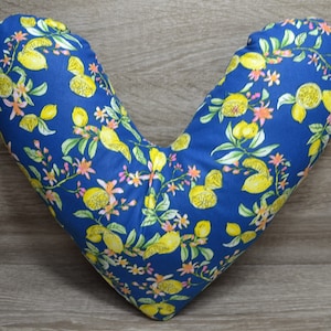 Könnte beinhalten: Ein blaues V-förmiges Kissen mit einem Zitronen- und Blumenmuster. Das Kissen ist aus Stoff und fühlt sich weich und bequem an.