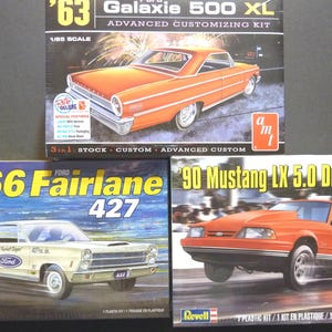 May include: Three model car kits are displayed. The top box features a '63 Ford Galaxie 500 XL in orange. Below is a '66 Ford Fairlane 427 in cream. The bottom right box shows a '90 Mustang LX 5.0 Drag Racer in orange.