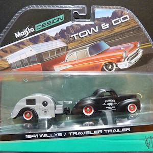 May include: A Maisto Design Tow & Go set featuring a black 1941 Willys Traveler Trailer and a black car with "Porky's Mobile BBQ" text. The trailer is silver with red-rimmed wheels. The packaging includes a vintage car graphic.