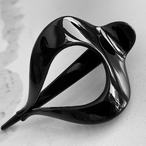 May include: A glossy black hair clip with a smooth, curved, teardrop-shaped frame. The accessory features an open center design with a pointed end and a rounded, wider base, showcasing a reflective surface and a solid, dark, monochromatic finish.