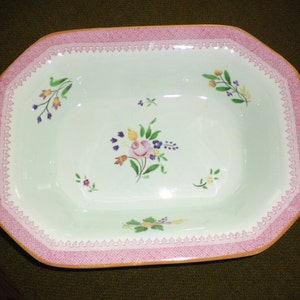 May include: A white octagonal serving dish with a pink and gold trim. The dish is decorated with a floral design in shades of pink, yellow, green, and purple.