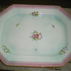 May include: A white octagonal serving platter with a light blue glaze and a pink and gold trim. The platter is decorated with hand-painted floral designs in shades of pink, yellow, and green.