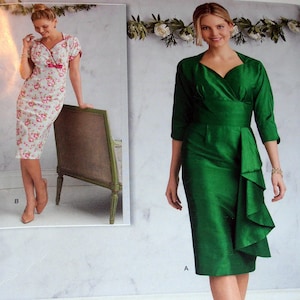 May include: Two women wearing dresses. The woman on the left is wearing a white dress with pink floral print and a pink bow. The woman on the right is wearing a green dress with a ruffle detail.