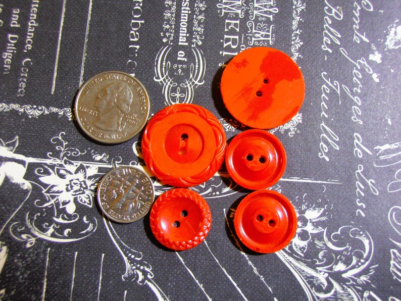 May include: Assortment of six red plastic buttons with two-hole centers. The buttons are various sizes and have different textures.