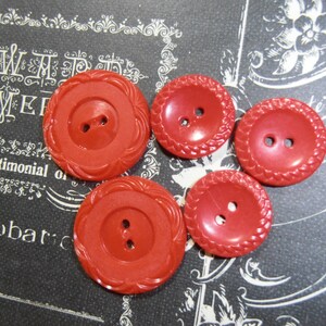 May include: Four red plastic buttons with two holes each. The buttons have a raised, textured design around the edges.