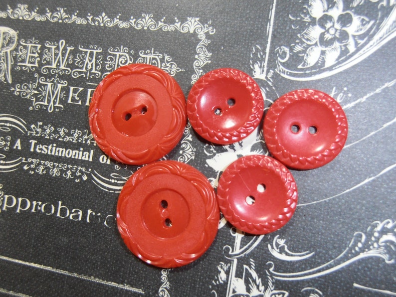 May include: Four red plastic buttons with two holes each. The buttons have a raised, textured design around the edges.