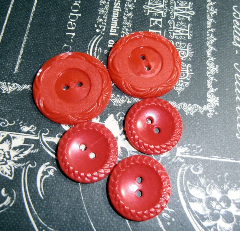 May include: Four red plastic buttons with two holes each. The buttons have different designs around the edges.