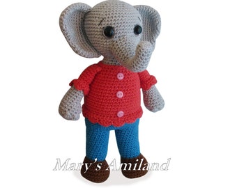 May include: A gray crocheted elephant wearing a red shirt with pink buttons and blue pants. The elephant has brown shoes and black eyes.