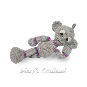 May include: A gray crocheted stuffed animal with pink and blue stripes. The animal has a long snout, large ears, and a friendly face.