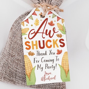 May include: A white tag with the text "Aw Shucks" in orange and yellow letters. The tag has a fall theme with illustrations of corn, leaves, and stars. The text "Thank You For Coming To My Party! Love, Michael" is printed below the main text.
