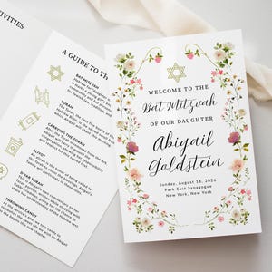 May include: A Bat Mitzvah invitation with floral accents. The invitation features the text "Welcome to the Bat Mitzvah of our Daughter Abigail Goldstein" and event details. A guide to the ceremony is also included.
