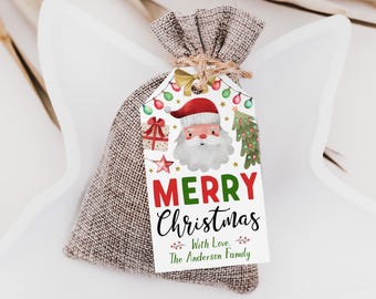 May include: A small brown burlap drawstring bag with a white rectangular gift tag attached by twine. The tag features a watercolor Santa Claus, a gift box, a star, a Christmas tree, and string lights. Text reads Merry Christmas With Love, The Anderson Family.