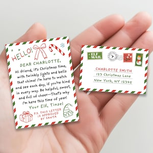 Puede incluir: Dos tarjetas navideñas, una con una carta para Charlotte y otra un sobre. La carta tiene un borde rojo y verde, con el texto "Hello! Dear Charlotte". El sobre está dirigido a Charlotte Smith.