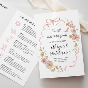 May include: A Bat Mitzvah invitation with a floral design. The invitation features the text "Welcome to the Bat Mitzvah of our Daughter Abigail Goldstein" with the date and location. A guide to the Bat Mitzvah is also included.