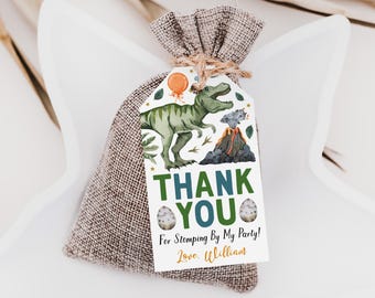 Puede incluir: Una bolsa de arpillera marrón con cordón y una etiqueta de papel rectangular atada con cuerda. La etiqueta muestra un dinosaurio verde, un globo naranja, un volcán y dos huevos moteados. Texto: THANK YOU For Stomping By My Party! Love, William.