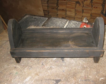 Op de afbeelding: Een klein houten bedframe geverfd in zwart met afgeronde randen en poten. Het bedframe is gemaakt van hout en heeft een eenvoudig ontwerp.