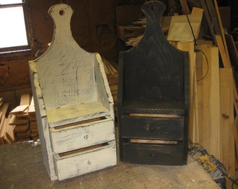 Op de afbeelding: Twee houten wandgemonteerde opbergunits met elk twee laden. Een unit is wit geverfd met zwarte slijtage en de andere is zwart geverfd.