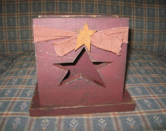 Op de afbeelding: Een rode houten doos met een stervormige uitsparing en een rood-wit geruit lint. De doos heeft een verweerde verflaag en is perfect voor het bewaren van kleine voorwerpen.
