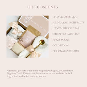 May include: A gift box with a ceramic mug, Himalayan bath salts, a handmade soap bar, green tea packets, fuzzy socks, a gold spoon, and a personalized card. The box is tied with a beige ribbon and includes the text "Thinking of You."
