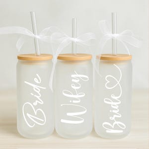 May include: Three frosted glass tumblers with bamboo lids and clear straws. The tumblers are labelled "Bride", "Wife", and "Bride" with a heart.