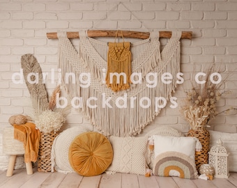 May include: A bohemian-style backdrop featuring a macrame wall hanging with a mustard yellow tassel, a woven basket with dried flowers, and a variety of pillows in cream and mustard yellow.