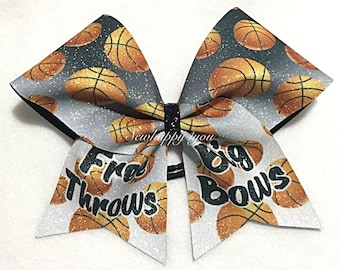May include: A large cheerleading bow with a basketball design. The bow has a black centre and is decorated with basketballs and the words "Free Throws Big Bows".